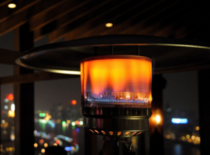 Outdoor heater with city lights background.