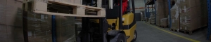 Yellow forklift moving pallet in aisle