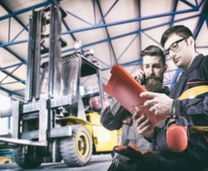 Warehouse workers inspecting forklift paperwork