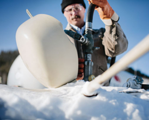 Man filling propane tank in snowy setting.