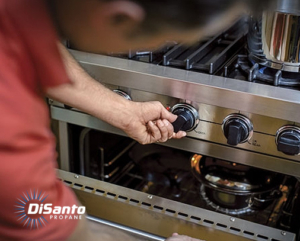 Person adjusting control knob on stove.