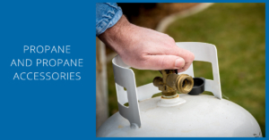 A person is holding the valve on an outdoor gas tank.