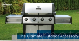 A grill sitting on top of grass near trees.