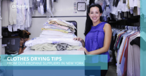 A woman standing next to a pile of folded clothes.