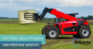 A red tractor is in the grass with a large green bucket.