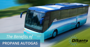 A blue bus driving down the street with trees in the background.