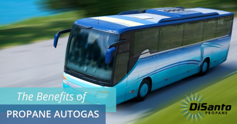A blue bus driving down the street with trees in the background.