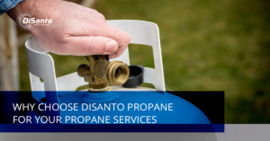 A person is holding the valve of an outdoor propane tank.