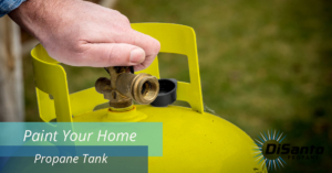 A person opening up the tank of an outdoor propane heater.