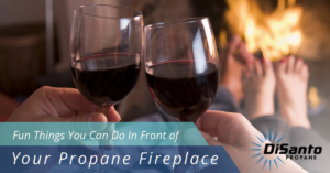 Two people holding wine glasses in front of a fireplace.