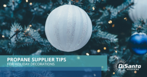 A white ball hanging from the side of a christmas tree.